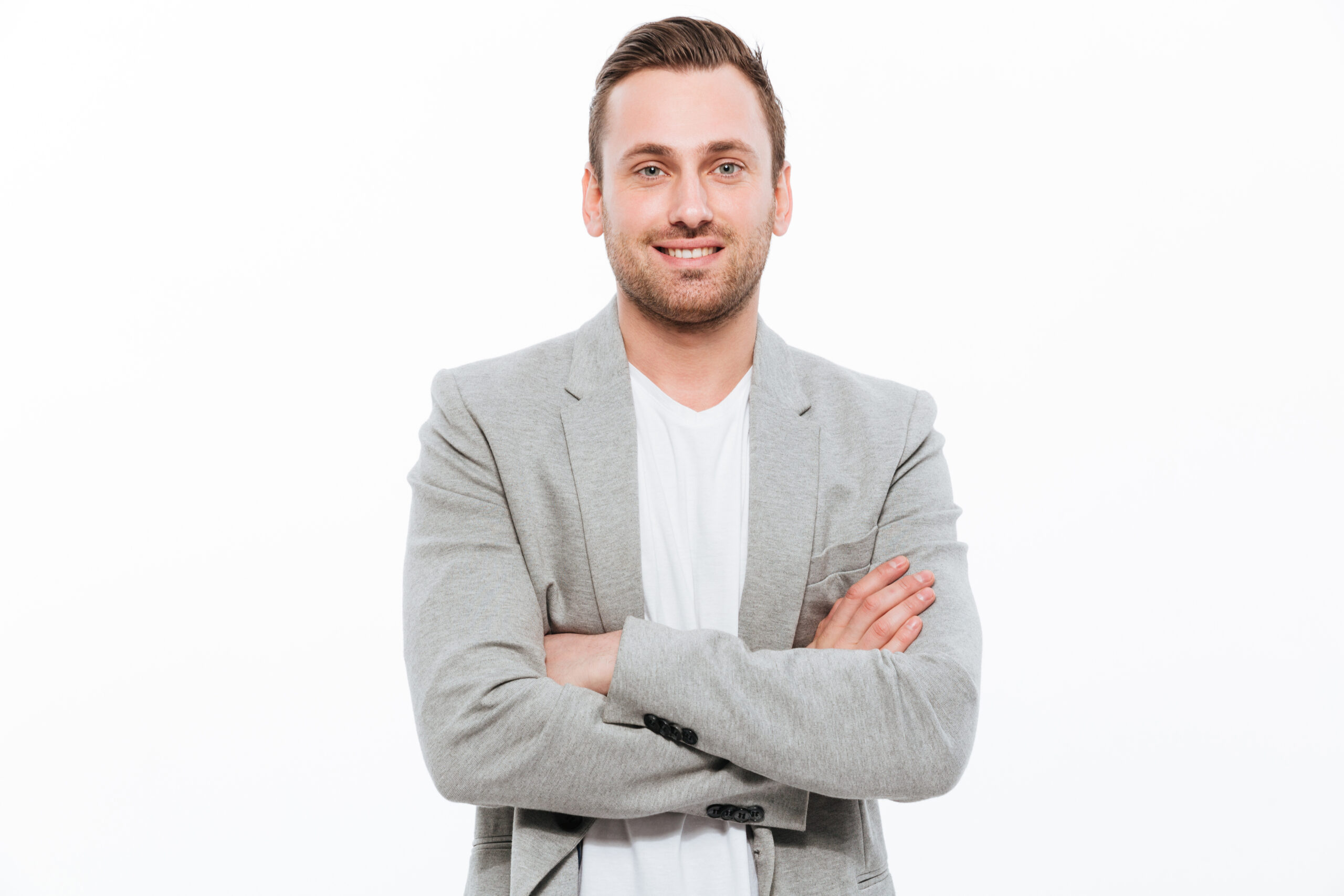Portrait of successful man having stubble posing on camera with Portrait of successful man having stubble posing on camera with broad smile keeping arms folded isolated over white background